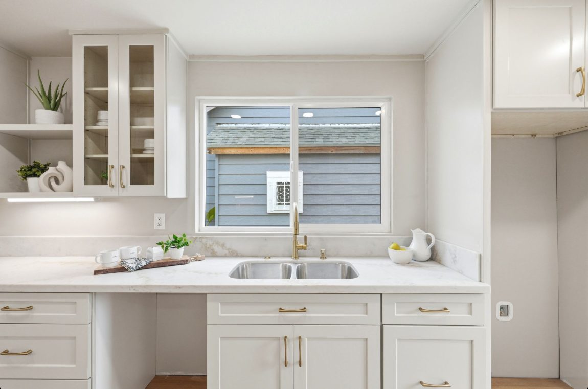 Kitchen sink run in Tapue Shaker with glass-front uppers and a quartz counter.