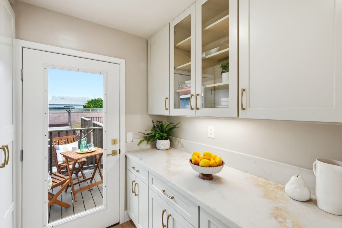 Kitchen run in Tapue Shaker with glass-front upper cabinets and a quartz counter.
