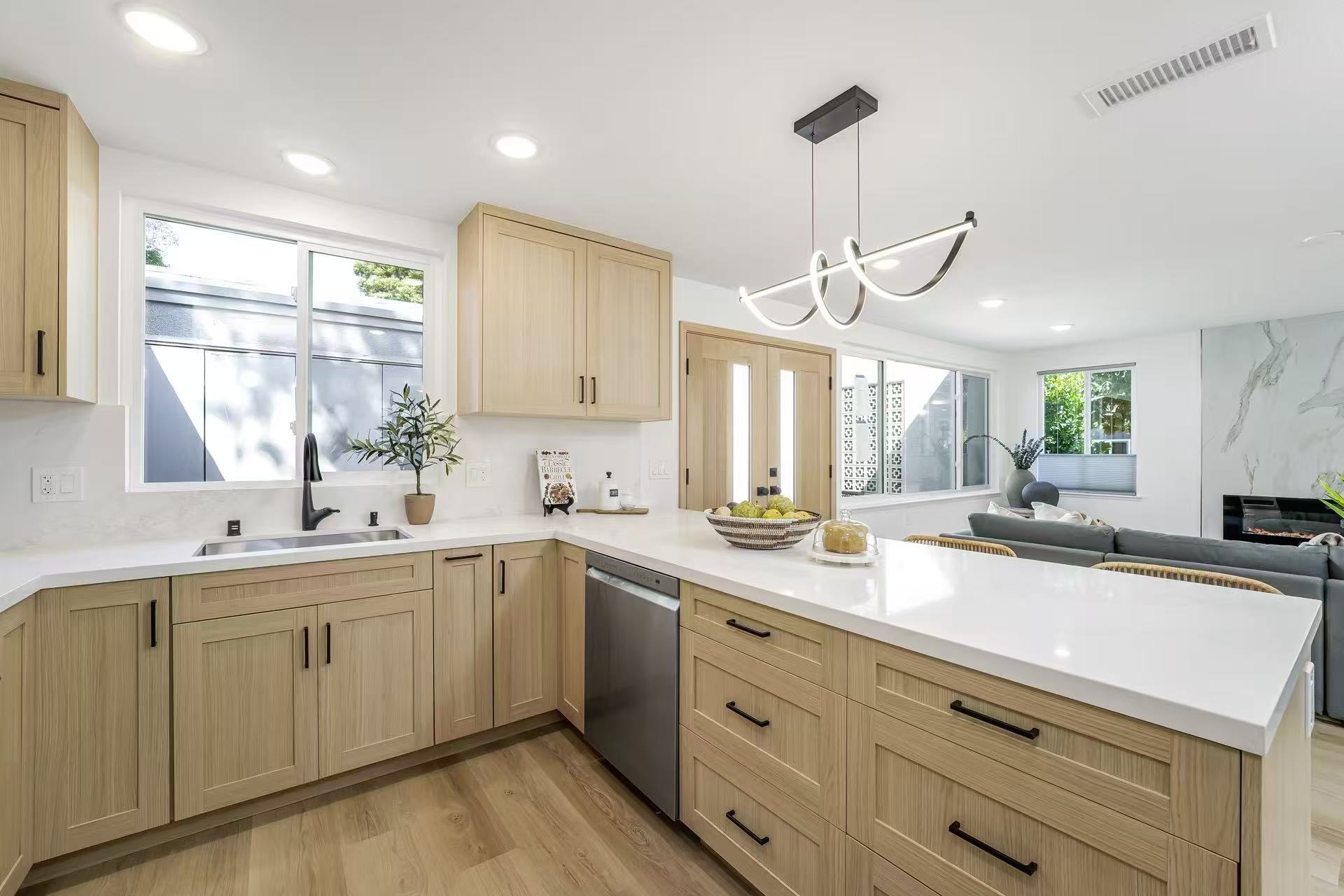 Light-wood kitchen with white quartz countertops and waterfall peninsula.