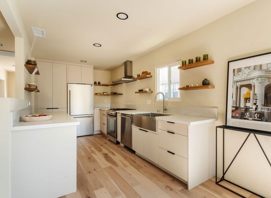 Compact white kitchen with floating wood shelves.