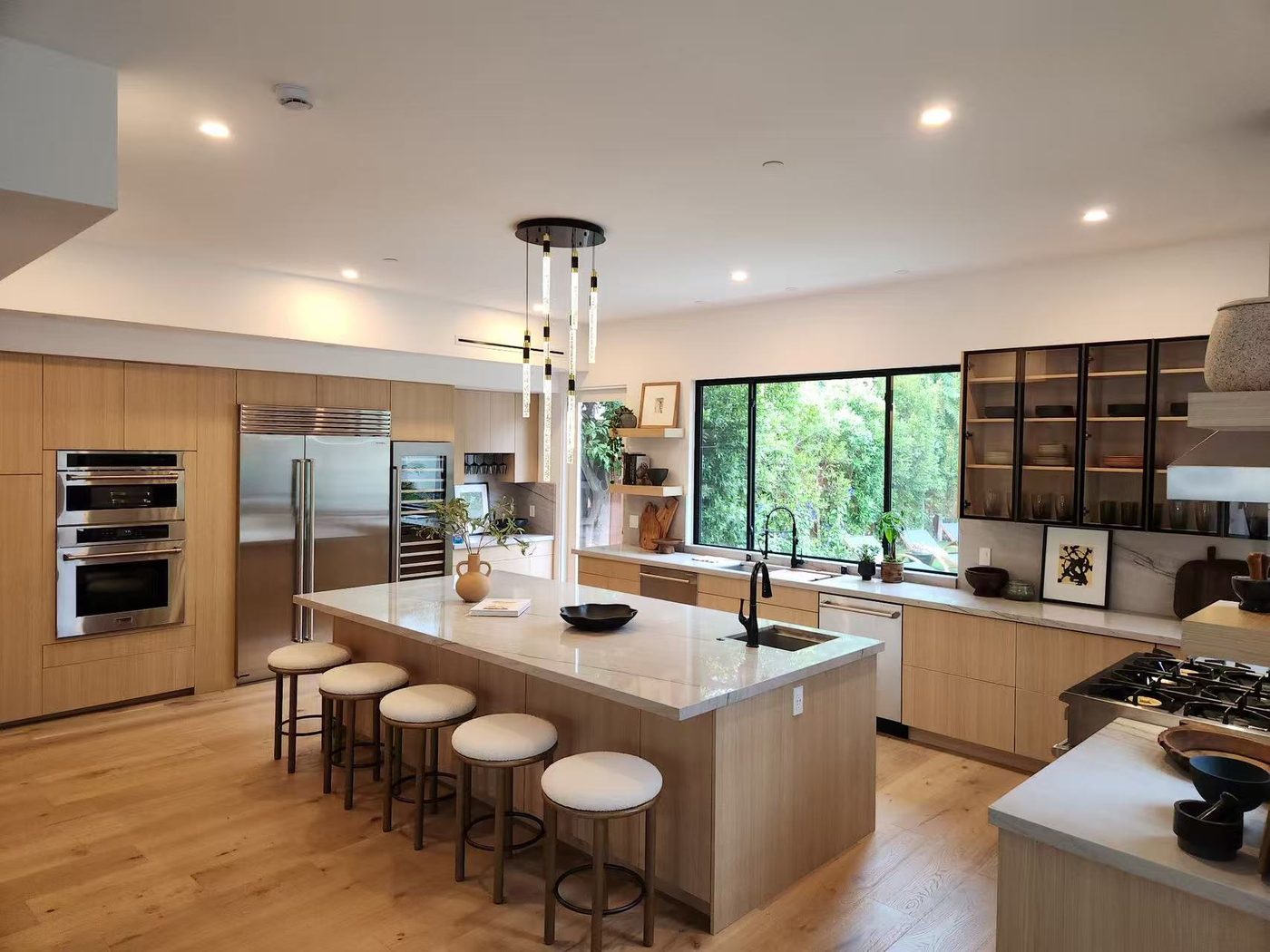 Open-plan light-oak kitchen with a large island and bar seating.