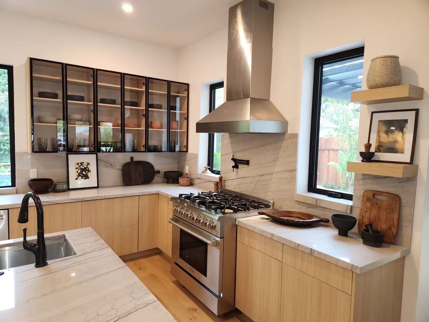 Oak kitchen with glass-front upper cabinets and a pro gas range.