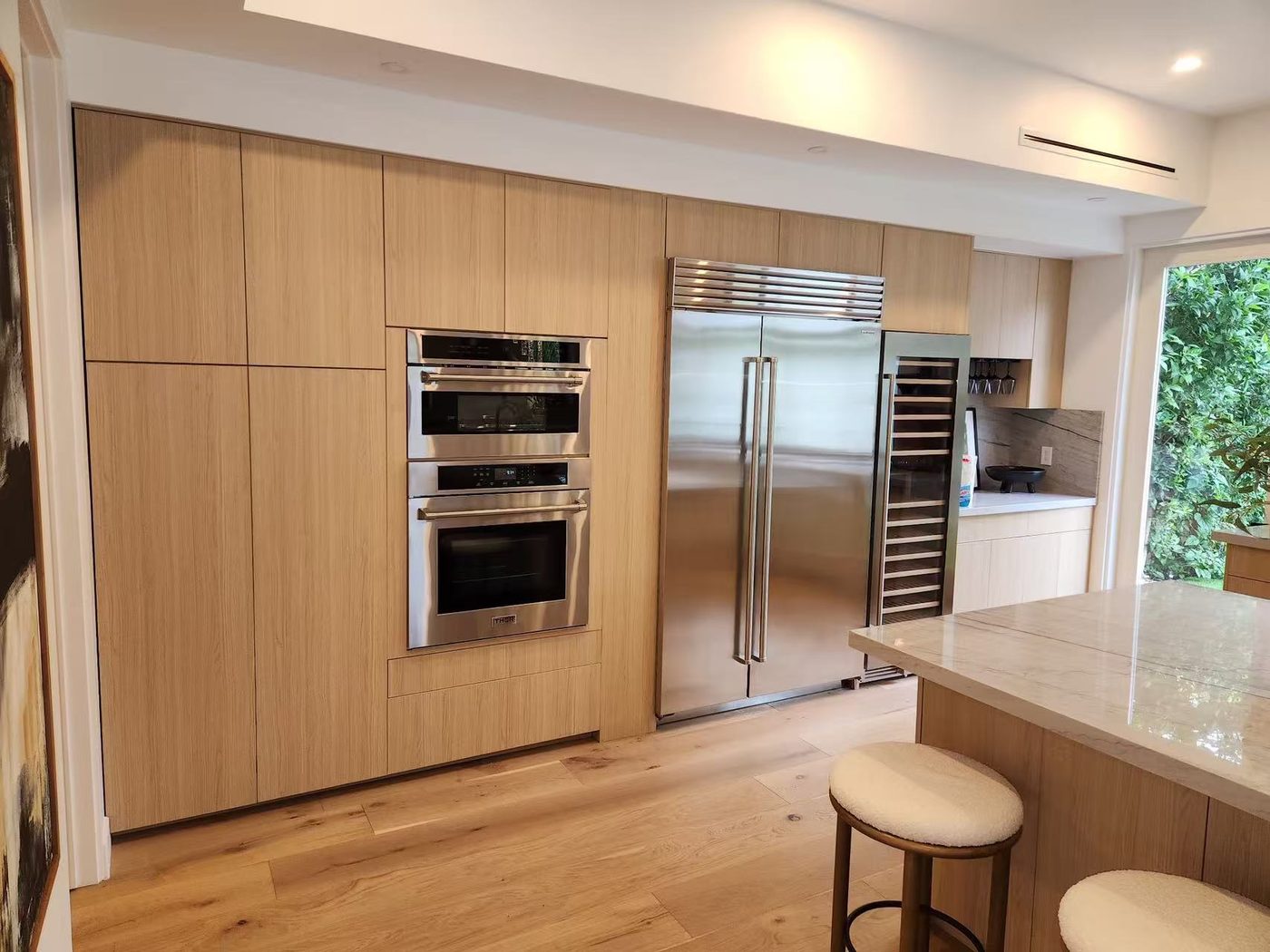 Tall oak cabinet wall with built-in double ovens and refrigerator column.