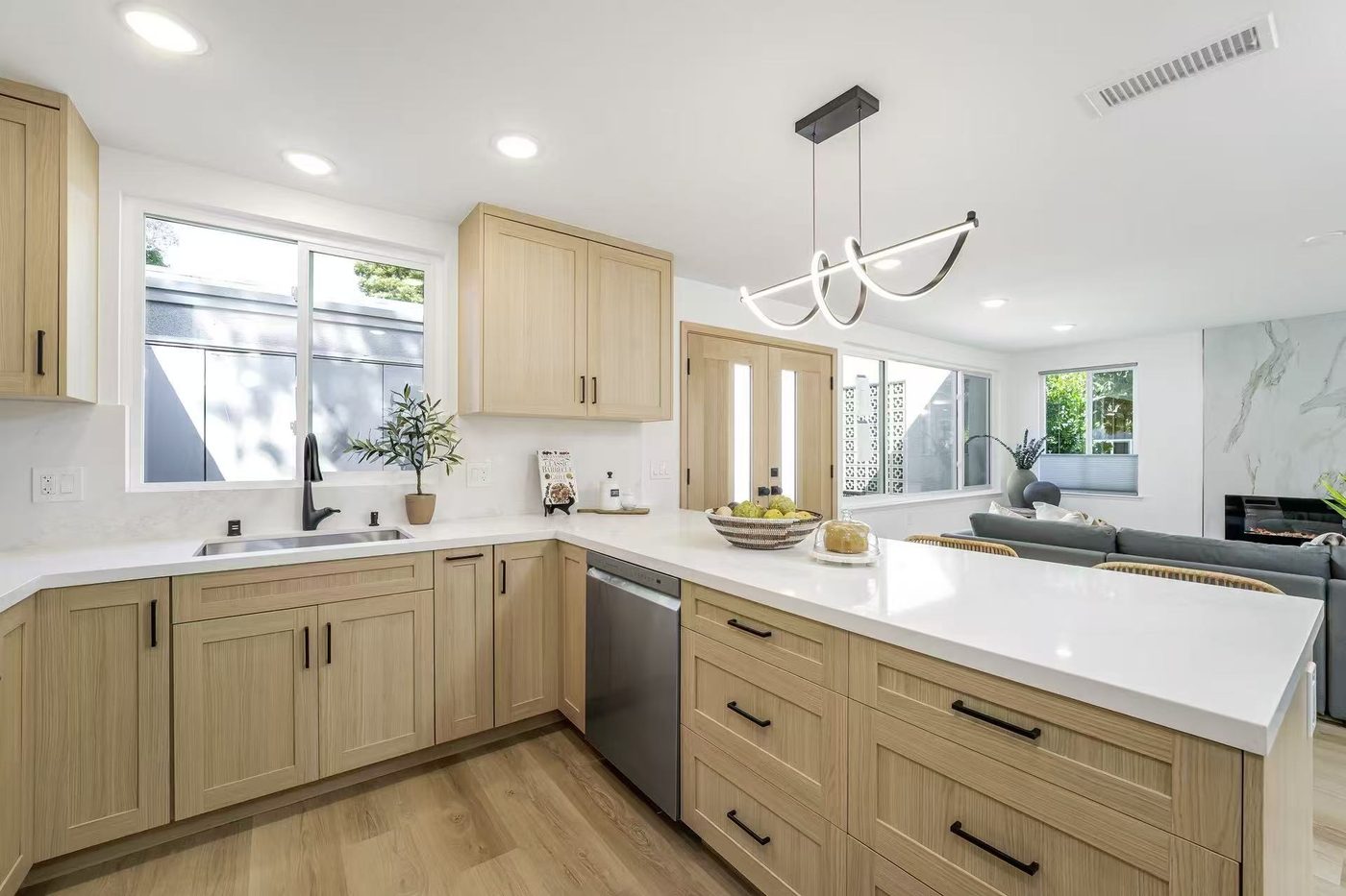 Light-oak kitchen with white quartz countertops and a peninsula.