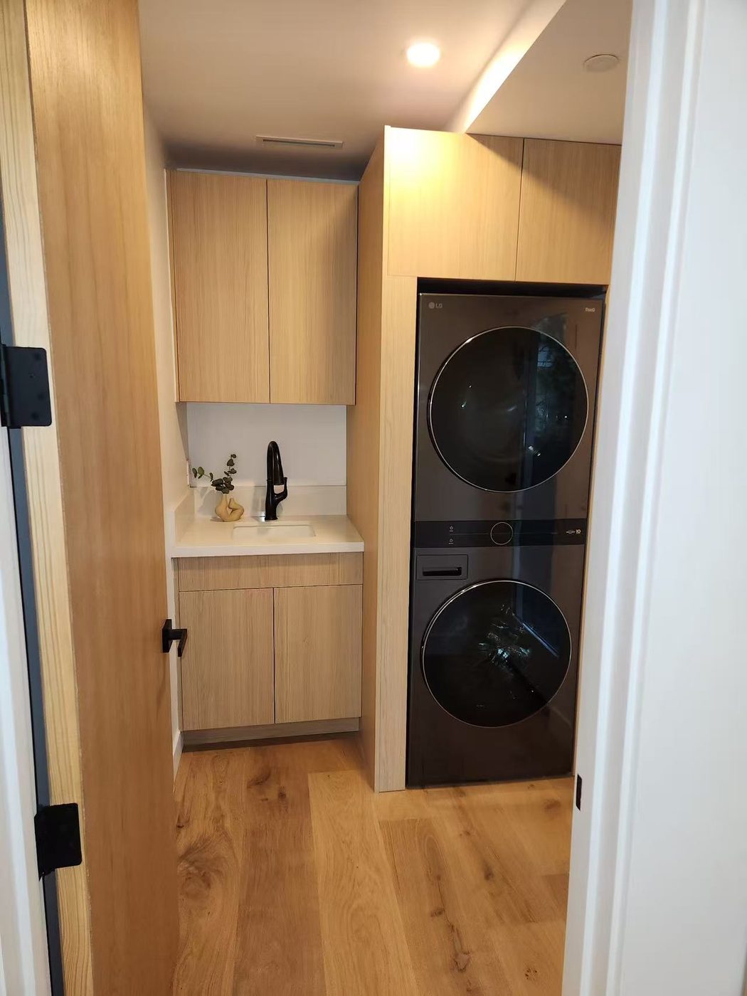 Laundry room with a stacked washer-dryer and oak cabinetry.