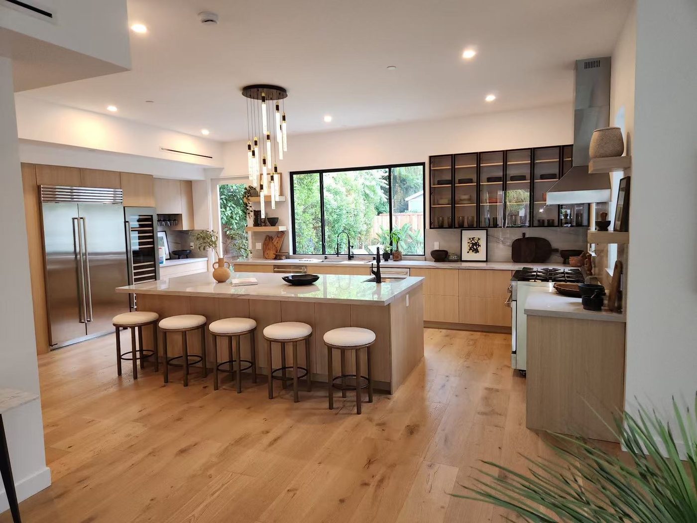 Wide oak kitchen with island, bar stools, and pendant cluster.