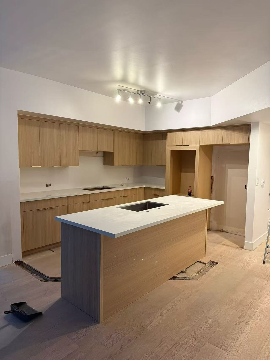 Oak kitchen island with pendant cluster and built-in double ovens.