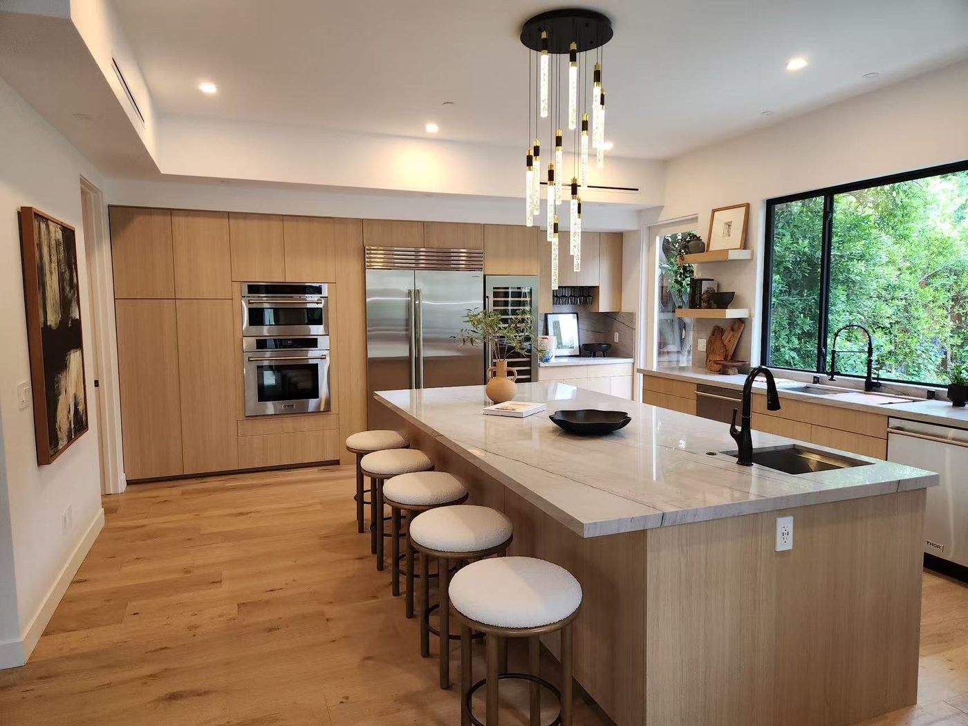 Open-plan oak kitchen with a waterfall-edge quartz island.
