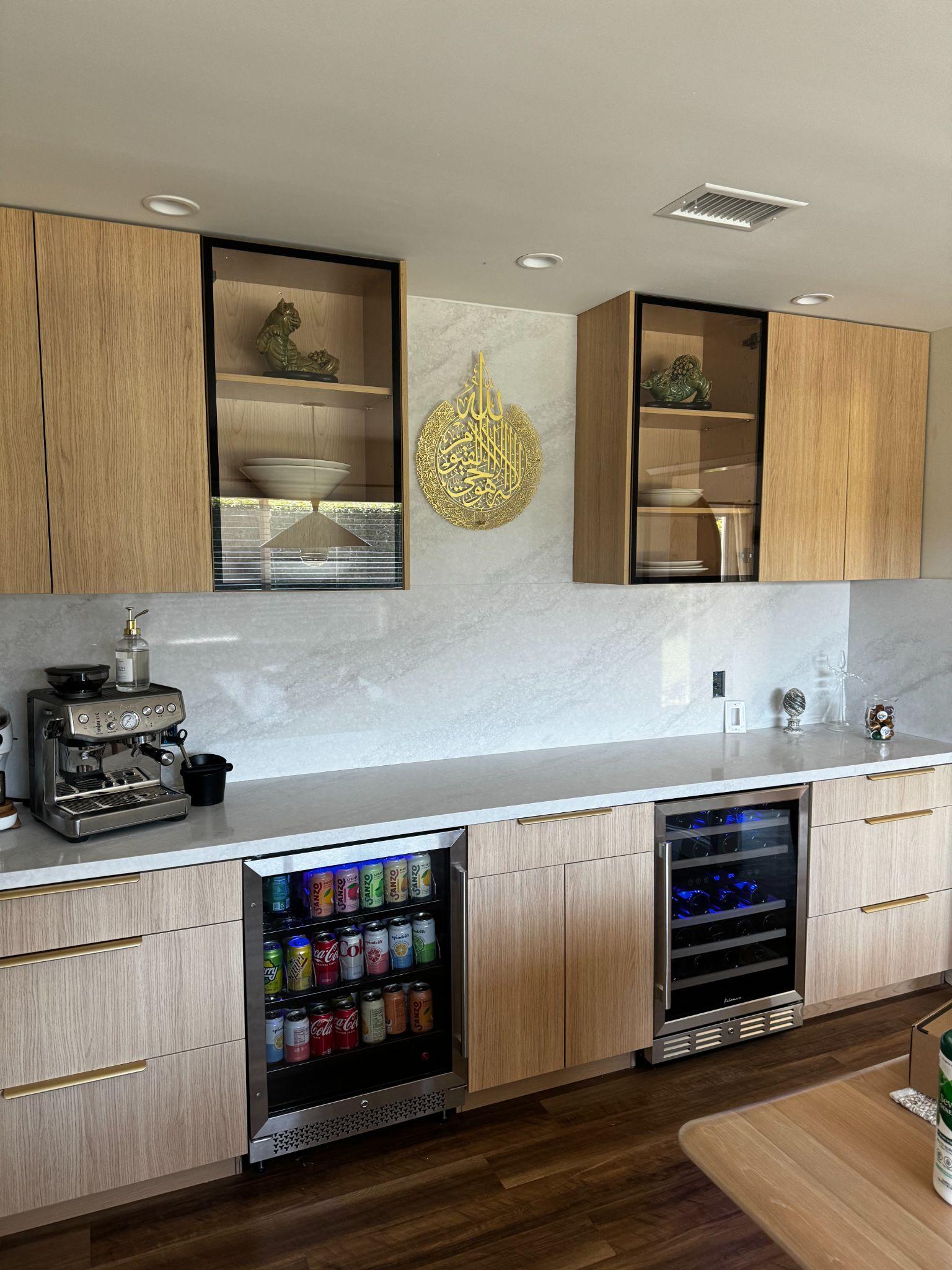 Built-in coffee and beverage bar with glass-front cabinets and marble backsplash.