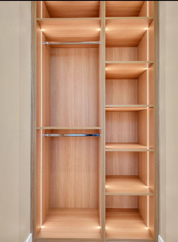 Oak reach-in wardrobe interior with adjustable shelves and twin hanging rails.